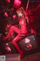 A woman in a red latex outfit sitting on a television.