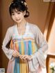 A woman wearing a colorful hanbok standing in front of a window.