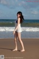 A woman standing on a beach next to the ocean.