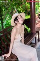 A woman in a white dress and straw hat sitting on a bench.