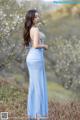 A woman in a blue dress standing in a field.