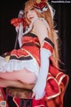 A woman in a red and white dress sitting on a stool.