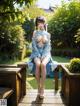 A woman in a blue dress sitting on a wooden bench.