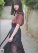 A woman in a black skirt and a brown blouse.